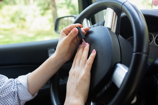 Woman is making manicure in the car.