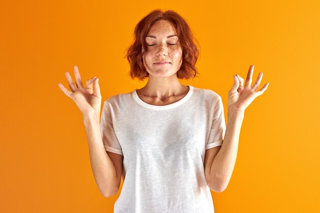 La donna sta meditando isolato in studio su sfondo arancione, mantenere la calma. concetto di yoga