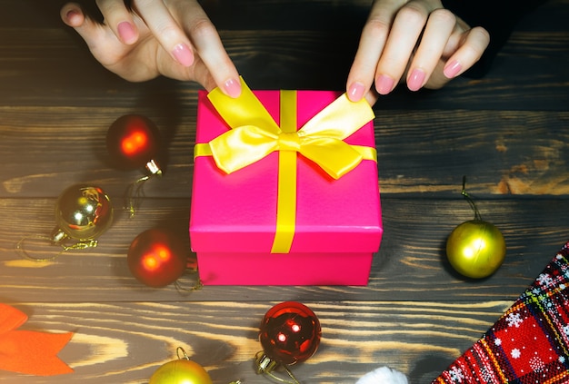Женщина пакует рождественские подарки. Поздравления родным и близким. Украшения на деревянном столе. Поздравления с новым годом. Уютное настроение и праздничное время. Скопируйте космическое место.