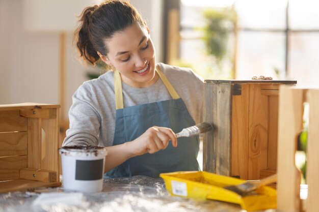 Woman is painting a wooden crate