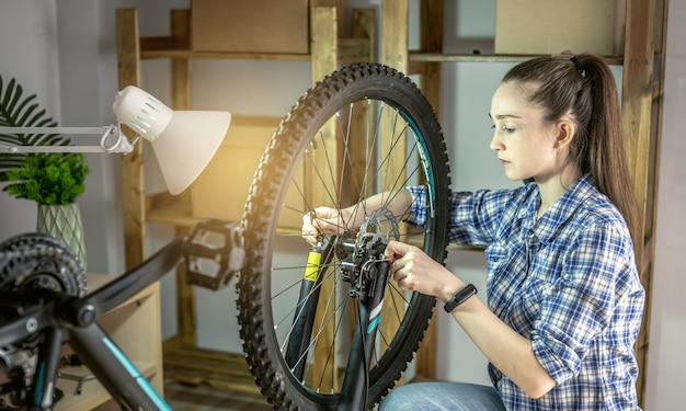 Женщина выполняет техническое обслуживание его горного велосипеда. Концепция крепления и подготовки велосипеда к новому сезону