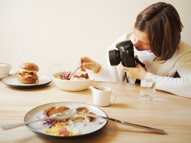 写真 女性はレストランの食べ物を写真撮影しています