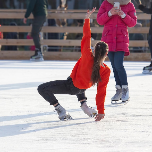 Foto donna è fotografata su una pista di pattinaggio sul ghiaccio. hobby e vacanze invernali