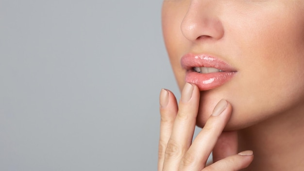 A woman is placing her hand on her lips in a gesture of quiet contemplation or secrecy she appears