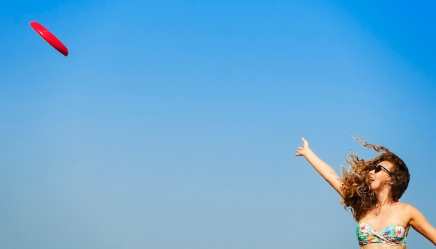 A woman is playing frisbee at the beach