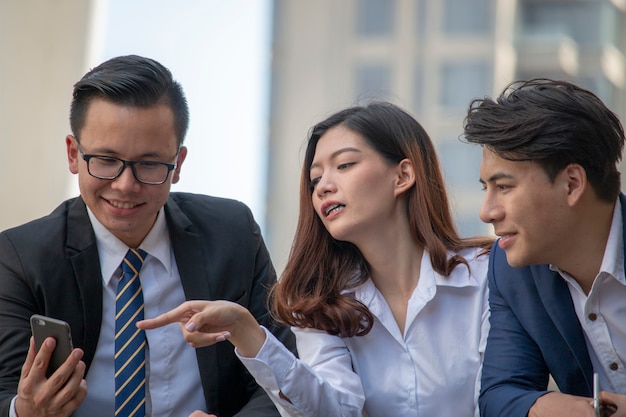 Photo woman is pointing at mobile phone with two men are watching