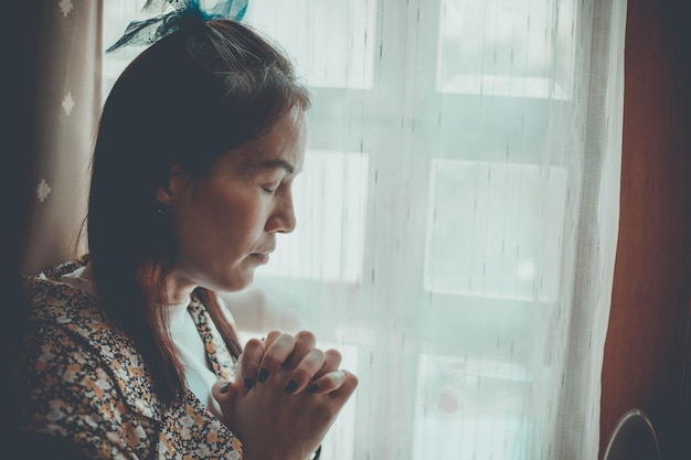 A woman is praying with her eyes closed