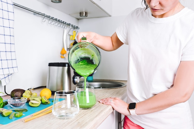 Una donna sta preparando un succo detox fatto in casa o un frullato vitaminico concentrato nel frullatore. stile di vita sano, alimentazione sportiva sana.