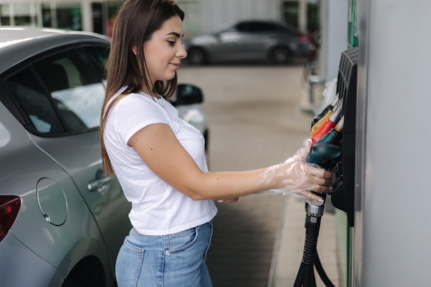 Woman is preparing for refueling at gas station female hand filling benzine gasoline fuel in car