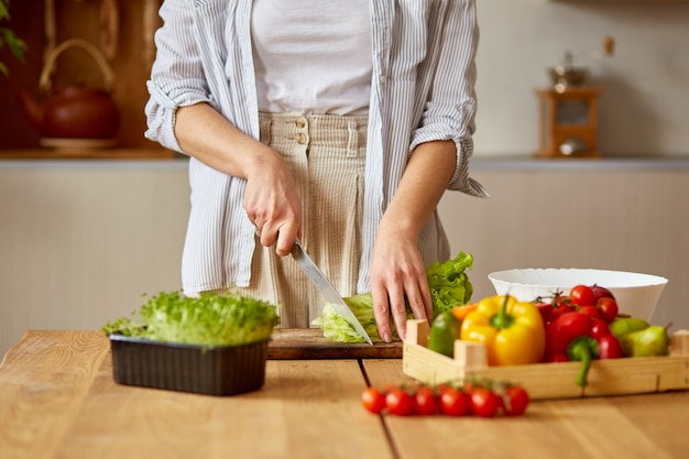 Woman is preparing vegetable salad in the kitchen