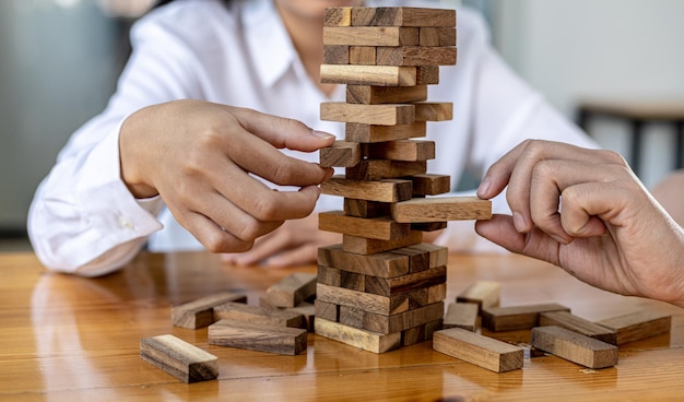 A woman is pulling a block of wood from a row and not breaking it down, like running a good business and solving problems. The concept of business management on risk.