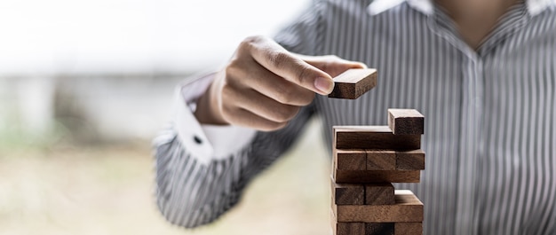 A woman is pulling a block of wood from a row and not breaking
it down, like running a good business and solving problems. the
concept of business management on risk.