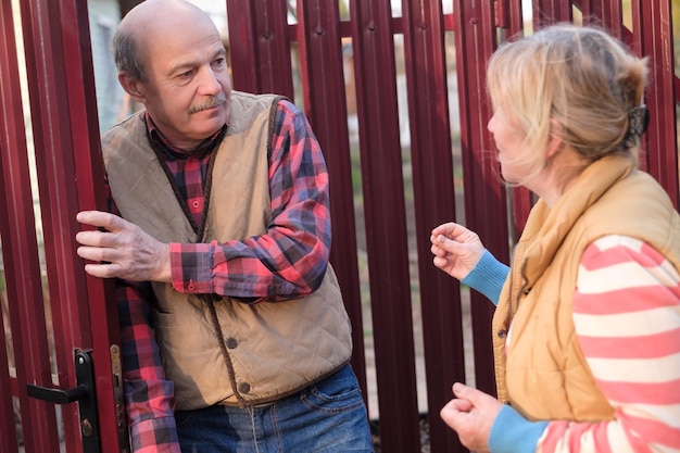 Woman is quarreling and having conflict with her neighbour at fence door