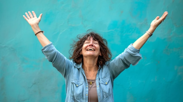 Foto una donna alza le mani in aria mentre si trova di fronte a un muro blu