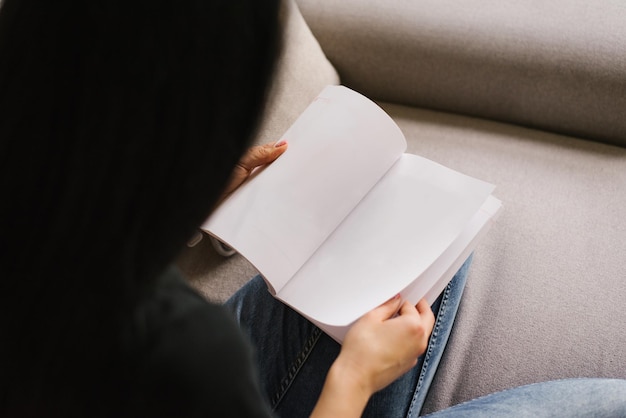 Woman is reading a book a mockup of a blank page View from behind the girl's shoulder on the book