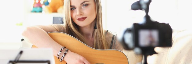 Woman is recording guitar playing on camera. learning to play\
guitar remotely concept