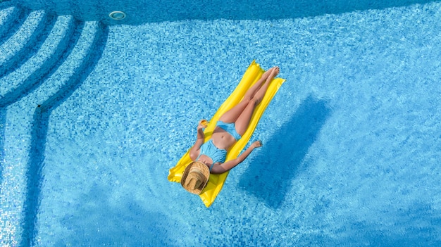 A woman is relaxing in the swimming pool on inflatable mattress