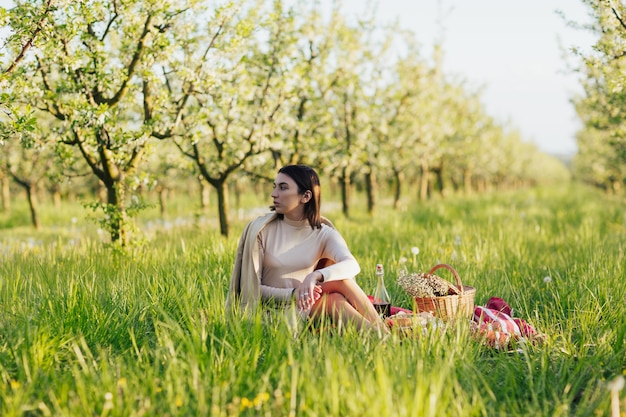 Woman is resting on a picnic in the spring blooming garden