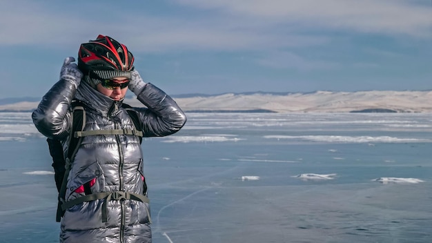 Woman is riding bicycle on the ice Girl is dressed in a silvery down jacket cycling backpack