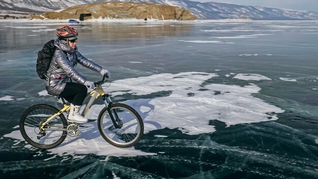 Woman is riding bicycle on the ice Tires on bike are covered wi