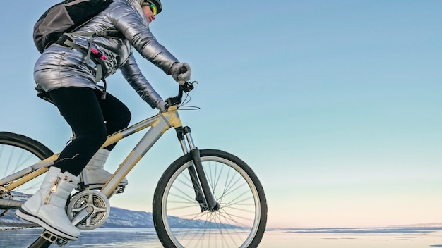 女性は氷の上で自転車に乗っています自転車のタイヤはwiで覆われています