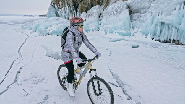 Woman is riding bicycle near the ice grotto The rock with ice c