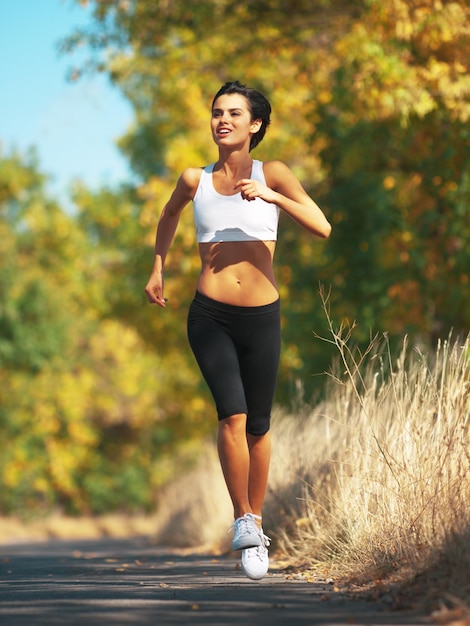 Photo woman is running on road cardio and fitness outdoor in nature with healthy and active person sport exercise and body training for marathon young female runner workout for health with energy