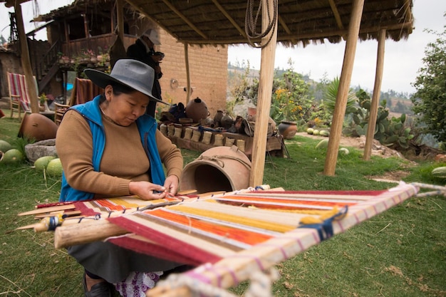 A woman is sewing a piece of wood with a hat on.