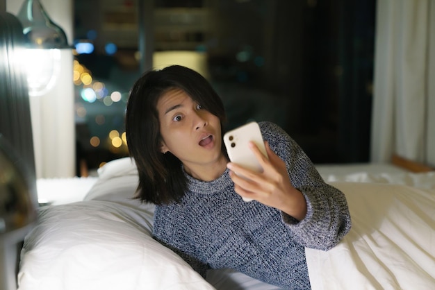 写真 電話を見ながら夜遅く起きた女性はショックを受ける