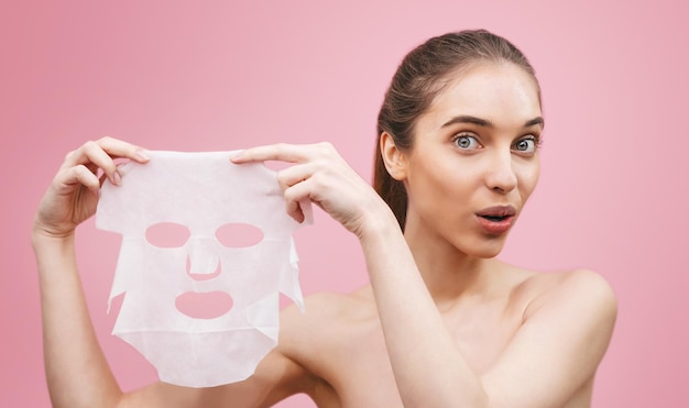 Woman is showing to the camera white cloth cosmetic mask for rejuvenating and eliminating defects Acne