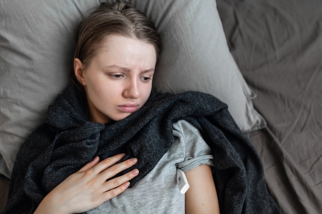 La donna è malata a casa sul letto. dolore al petto coronavirus (covid-19) i sintomi di un'infezione da virus coronarico comprendono respiro corto, dolore toracico. per alcune persone, può portare al polmone