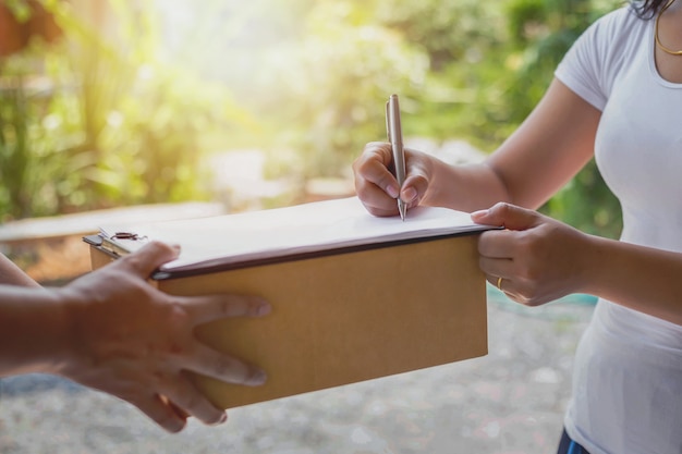 Foto la donna sta firmando i documenti che il personale addetto alla consegna ha fornito per confermare il concetto di servizio di consegna della ricevuta del pacco