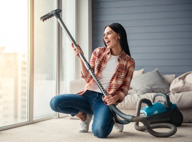 Woman is singing and smiling while cleaning floor