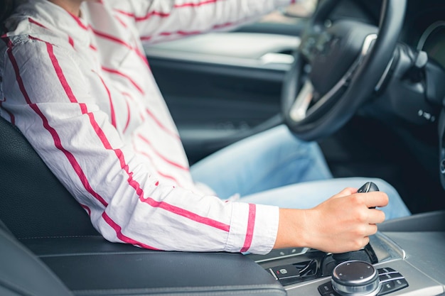 A woman is sitting in a car with the steering wheel on the steering wheel.