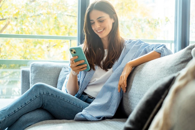 a woman is sitting on a couch with a phone