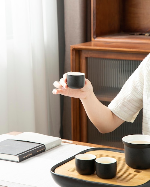 A woman is sitting at a desk with a book and a cup of coffee.