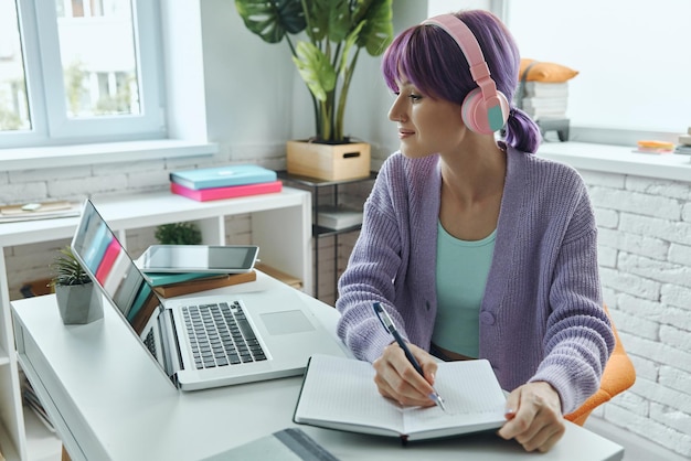 a woman is sitting at a desk with a laptop and a book on her desk