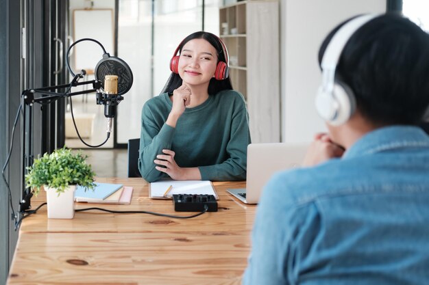 한 여자 가 마이크 와 노트북 을 들고 책상 에 앉아 있다