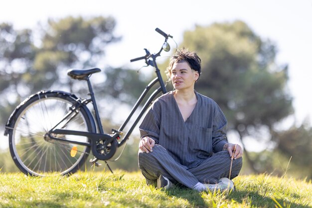 A woman is sitting on the grass next to a bicycle