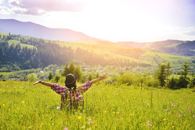 The woman is sitting on the grass in the mountains