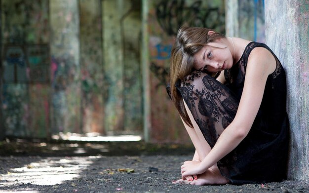 a woman is sitting on the ground with her head down