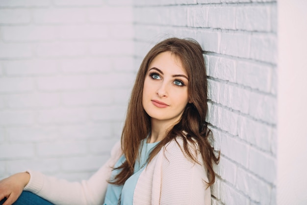 Woman is sitting near a brick wall