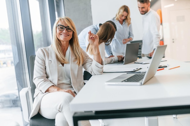 Woman is sitting and smiling Group of professional business people is in the office