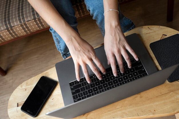 Woman is sitting on a sofa and using a laptop at wooden table