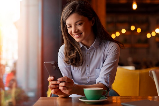 a woman is sitting at a table with a phone and a cup of coffee