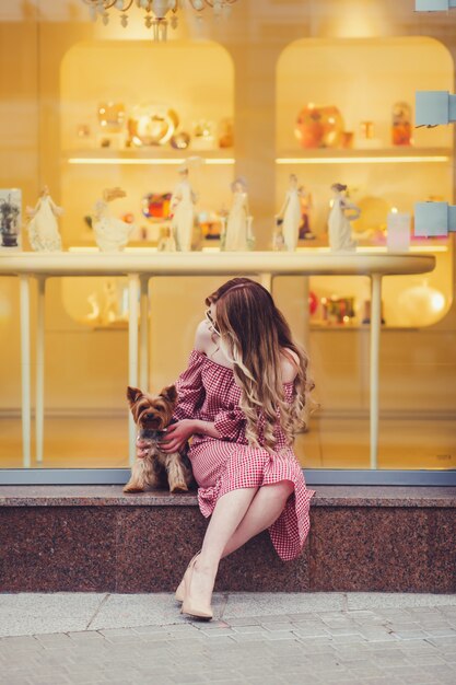 女性は小さな犬と一緒に座っています。