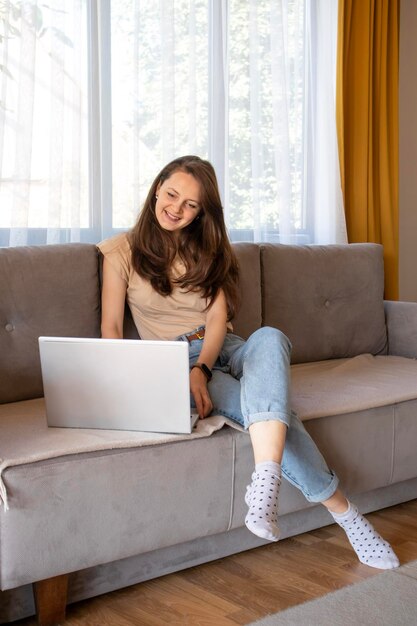 A woman is smiling while talking with someone remotely A girl is working from home online with a laptop