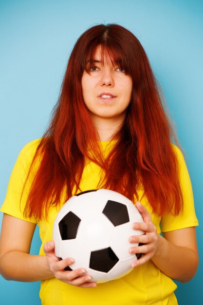 Foto la donna è tifosa di calcio in maglietta gialla con pallone da calcio su sfondo blu