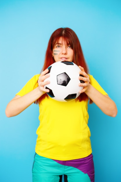Женщина - болельщик в желтой футболке с футбольным мячом на синем фоне
