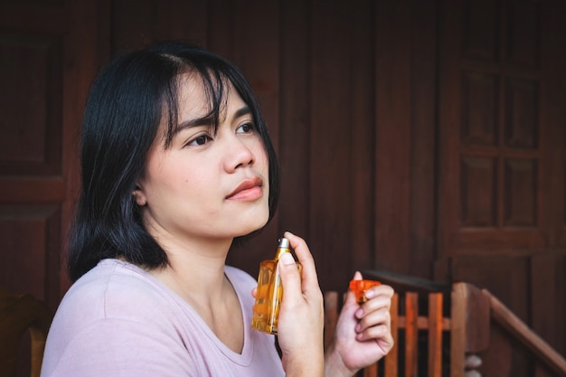 Woman is spraying perfume on her neck